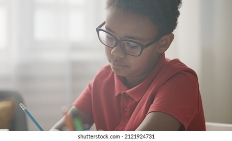 Serious african american schoolboy writing test at desk, having lot of homework - Powered by Shutterstock