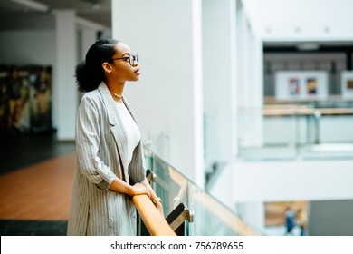 Serious African Business Student Woman Standing At Railing In Business Center Or Shopping Mall. Side View. Lifestyle, Leisure And People Concept.