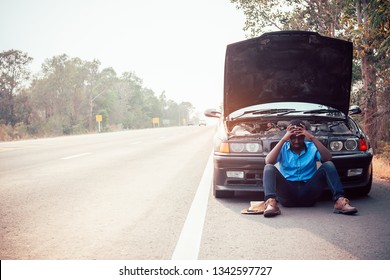 Serious African Man Holding His Head By Hands Standing Near His Old Broken Car  With Raised Hood On The Highway Road