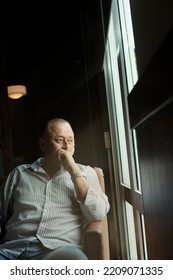 Serious Aged Male Pensioner Stand By Picture Window At Home