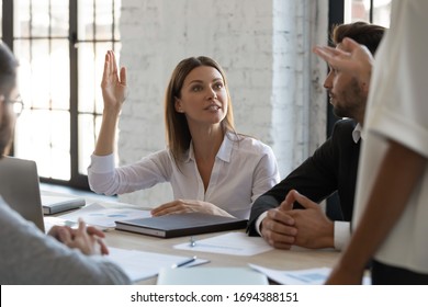 Serious ambitious businesswoman raise hand ask question to diverse presenter at meeting. Woman disagree with auditor opinion and show activity at teambuilding with multiethnic colleagues. - Powered by Shutterstock