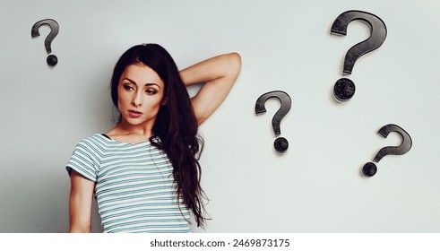 Serious angry woman wants understanding looking down in casual clothing with question signs around on blue studio background with empty copy space. Closeup banner portrait - Powered by Shutterstock