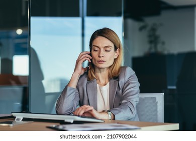 Serious And Anxious Business Woman Talking On The Phone, Working In A Modern Office At The Computer, Close-up Photo Of A Business Conversation