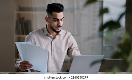 Serious Arabian Young Business Guy Male Professional Worker Employee Type On Computer Keyboard Copy Paper Text At Electronic Form Focused Hispanic Man Compare Documents Check Online Financial Report