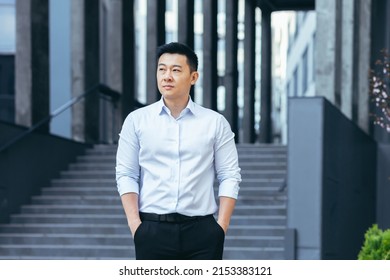 Serious Asian Businessman Holding Hands In Pockets Looking Sideways Wearing Shirt Outside Office