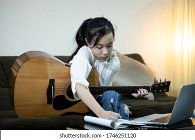 Serious Asian Child Girl Is Creating Works,trying Hard About Writing A New Songs,female Student Playing Guitar And Composing A Song,write A Music In Notebook,activities During Quarantine,stay Home