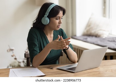 Serious Asian freelance worker woman in trendy wireless headphones talking on video call, using laptop computer for online business communication with client, speaking on Internet conference - Powered by Shutterstock