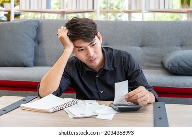 Serious Asian Man Calculating Budget Expenses Receipt Using Calculator Sitting In Living Room At Home, Personal Finance Concept