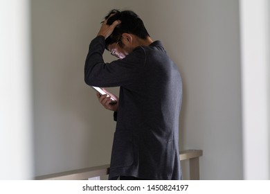 Serious Asian Man Looking At Mobile Phone