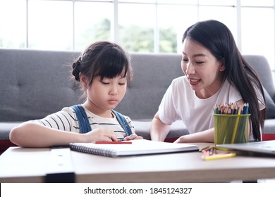 Serious Asian mother is teaching little girl child for drawing and Painting with wooden colored pencils on paper for imagination in living room. Family with Homeschool and educational concept - Shutterstock ID 1845124327