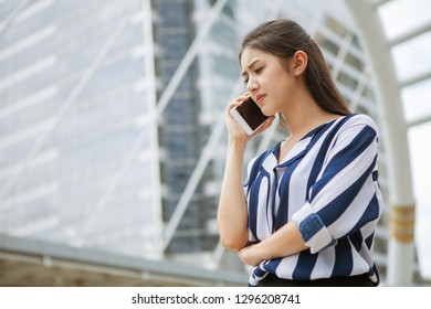 Serious Asian Young Business Woman Talking On Mobile Phone In Urban City . Outdoor.