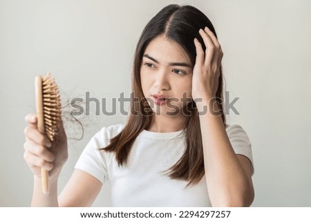 Serious asian young woman holding brush holding comb, hairbrush with fall black hair from scalp after brushing, looking on hand worry about balding. Health care, beauty treatment, hair loss problem.