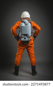Serious astronaut is standing in the space suit and helmet on the gray background. Back view. - Shutterstock ID 2271493877