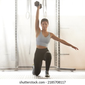 Serious athletic woman weight lifting for muscle strength. Training, fitness and active young female doing exercise workout at an indoor gym for strong toned body and healthy lifestyle.
