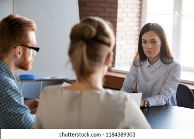 Serious Attentive Female Boss Listening To Employees Reporting About Work Results, Focused Applicant Looking At Hr At Job Interview, Confident Businesswoman Thinking Of Difficult Group Negotiations