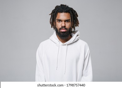 Serious Attractive Handsome Young African American Man With Dreadlocks 20s In White Casual Streetwear Hoodie Posing Looking Camera Isolated On Grey Color Wall Background Studio Portrait