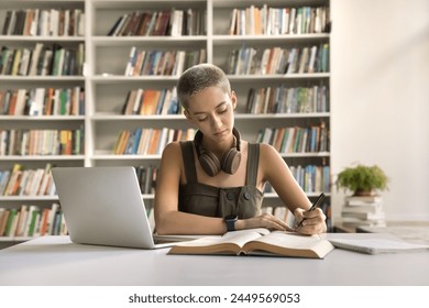 Serious attractive student girl learns topics, jotting information, write essay, summary or exercise in copybook, engaged in self-education, personal development, studying process in university - Powered by Shutterstock