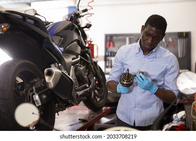 Serious auto mechanic repairing motorcycle part in garage. High quality photo - Powered by Shutterstock