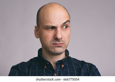 Serious bald man with raised eyebrow looking away