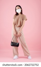 Serious Beautiful Young Woman In Protective Mask, T-shirt And Wide Pans Holding Small Bag And Looking At Camera