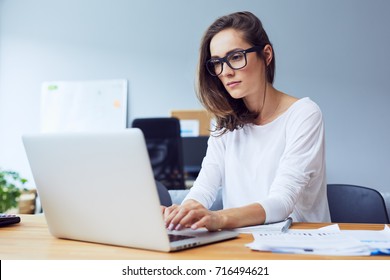 Serious Beautiful Young Woman Typing On Laptop In A Bright Modern Office