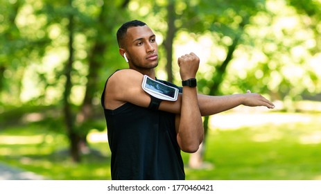 Serious Black Athlete Stretching His Arm And Enjoying Music After Jogging At Green Park, Panorama