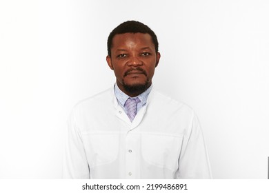 Serious Black Doctor Man With Small Beard In White Coat Bright Shirt Isolated On White Background. Adult Black African American Physician Therapist Portrait, Attractive Practitioner Family Doctor