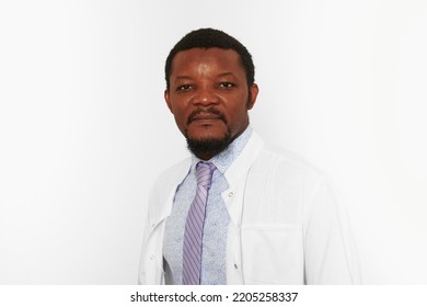 Serious Black Doctor Man With Small Beard In White Coat Bright Shirt Isolated On White Background. Adult Black African American Physician Therapist Portrait, Attractive Practitioner Family Doctor