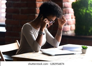 Serious Black Female Sitting At Table Talking On Mobile Phone With Boyfriend Solve Difficult Situation, Relationship Problems. Young Businesswoman Communicating On Cell Having Unpleasant Conversation