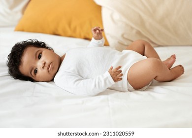 Serious black little child girl or boy in clothes lies on white comfort bed in bedroom. Health care, newborn, childhood, child care, parenthood at home, ad and offer, full length - Shutterstock ID 2311020559
