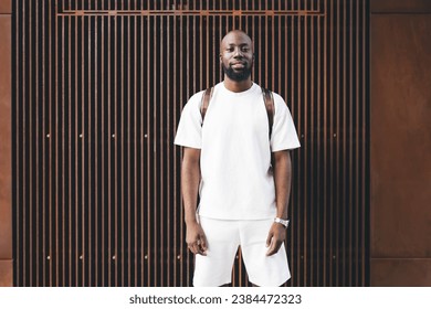 Serious black man with backpack standing near wall - Powered by Shutterstock