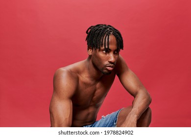 Serious Black Man Kneeling On Red Background