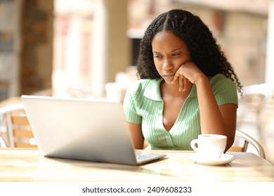 Serious black woman checking laptop in a bar terrace - Powered by Shutterstock