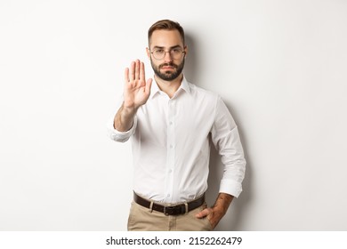 Serious boss in glasses showing stop sign, telling no, forbidding something, standing over white background