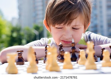 Serious Boy Playing Chess Outside In The Summer