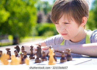 Serious Boy Playing Chess Outside In The Summer