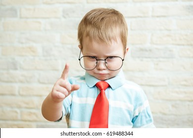 Serious boy standing with a finger in big glasses. The concept of the evil boss. - Shutterstock ID 619488344