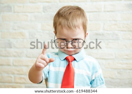 Serious boy standing with a finger in big glasses. The concept of the evil boss.
