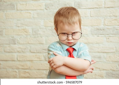 Serious boy stands with his hands in big glasses. The concept of the evil boss - Shutterstock ID 596587079