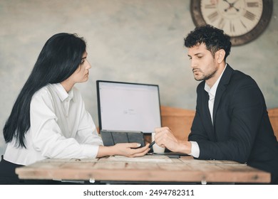 Serious business meeting in office between Hispanic man and woman co-worker using technology wireless digital tablet on desk, discussing work, professional expression, teamwork partnership concept - Powered by Shutterstock