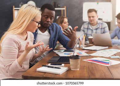 Serious business partners working in modern office. Two worried multiethnic coworkers discussing new project while working on laptop, copy space - Shutterstock ID 1070365799