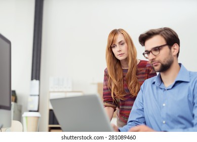 Serious Business Partners Working On A Laptop With The Woman Looking Over The Mans Shoulder As They Study Information On The Screen