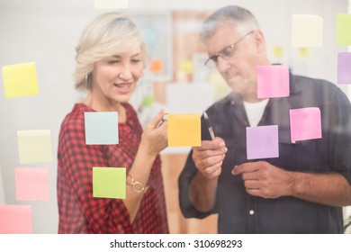 Serious Business Team Pointing Post Its On The Wall At Office