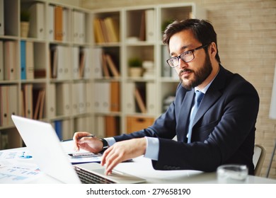 Serious Businessman Browsing In Laptop At Workplace