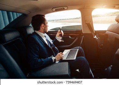 Serious Businessman In A Car With Laptop