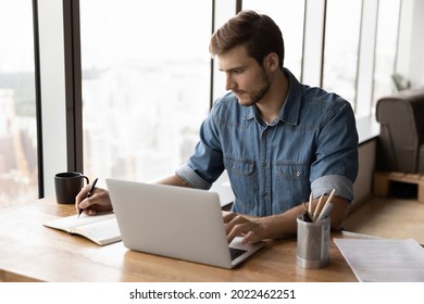Serious businessman, employee, entrepreneur working at laptop and writing, checking electronic schedule, agenda app, planning daily task in notebook. Manager talking to client online, taking notes