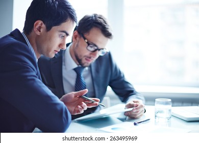 Serious businessman explaining data to his colleague at meeting - Powered by Shutterstock