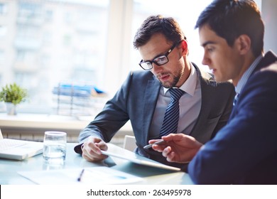 Serious businessman listening to his colleague explanations at meeting - Shutterstock ID 263495978