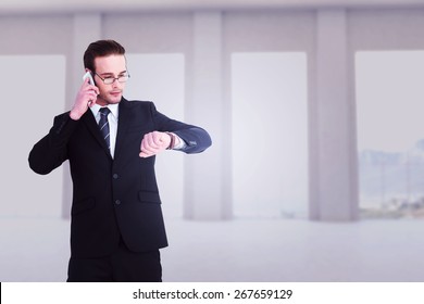 Serious businessman phoning while checking time against room overlooking ocean