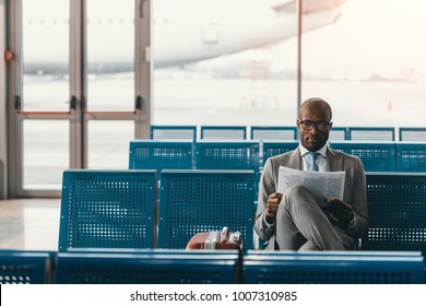 serious businessman reading newspaper waiting for flight at airport lobby - Powered by Shutterstock